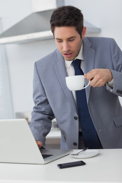 商人喝着咖啡看着笔记本电脑