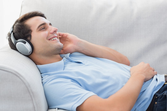 快乐的人躺在沙发上享受音乐