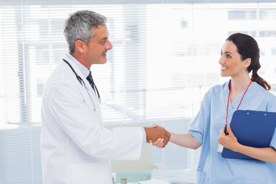 微笑的医生与护士在医务室握手