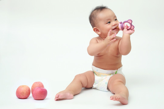 胖胖婴儿坐着啃食苹果汁