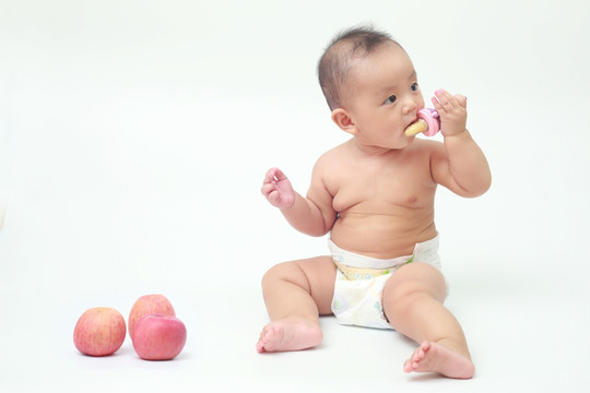 胖胖婴儿坐着啃食苹果汁