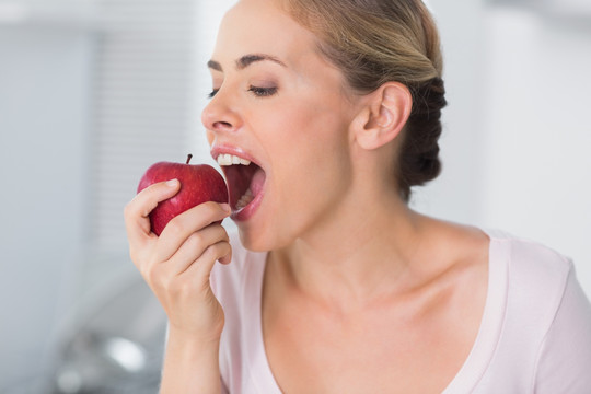 在她的厨房里大嚼苹果的女人