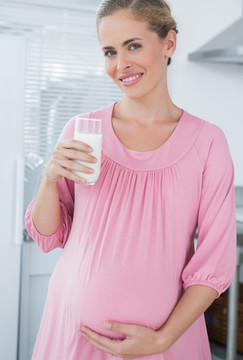 在厨房里喝牛奶的孕妇