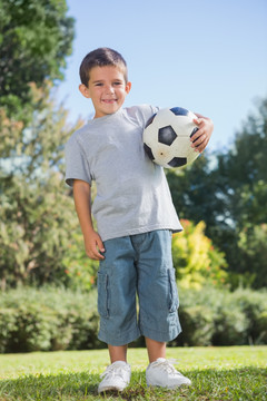 抱着足球在公园里的男孩