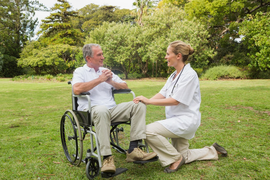 男子坐在轮椅上和护士在公园里