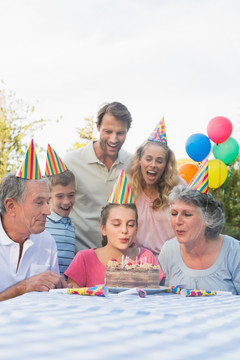 幸福的大家庭在公园里吹生日蜡烛