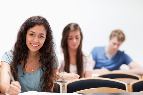微笑的年轻学生坐在教室里