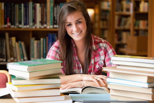 微笑的学生在图书馆里里阅读书籍