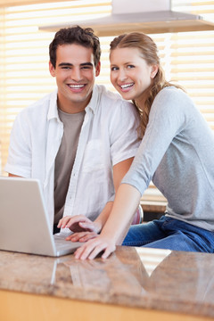 年轻夫妇微笑着在厨房里上网
