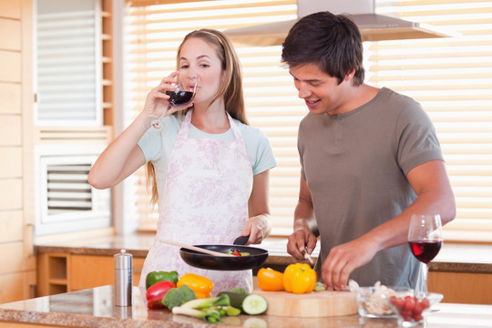 年轻夫妇在做晚饭时喝红葡萄酒