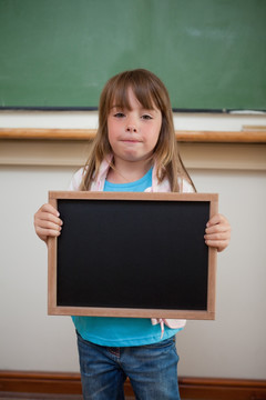 一个小女孩在教室里拿着小黑板