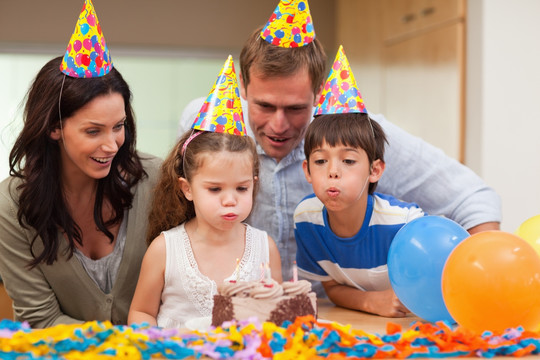 男孩帮助妹妹吹生日蛋糕上的蜡烛