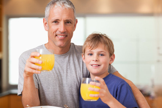 男孩和他的父亲在厨房里喝果汁