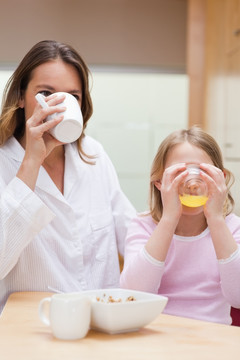 母亲和她的女儿在厨房里喝果汁