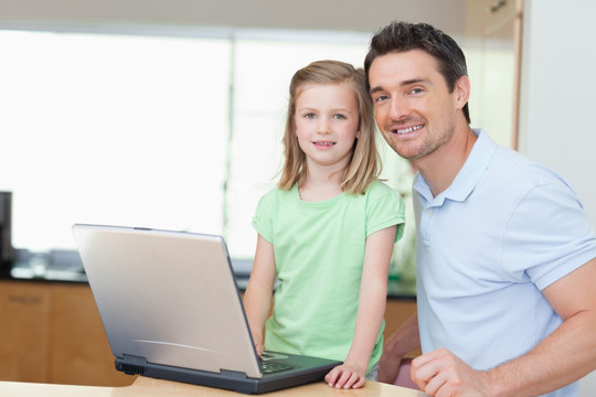 父亲和女儿一起使用笔记本电脑