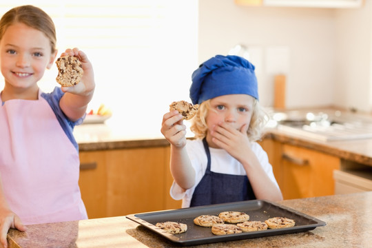 姐弟在厨房里展示他们的饼干