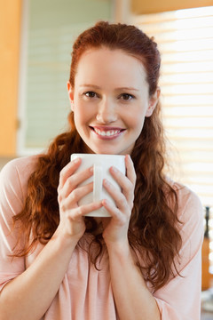微笑的年轻女人在喝一杯咖啡