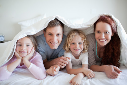 幸福的一家人盖着被子趴在床上