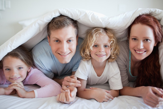 幸福的一家人盖着被子趴在床上