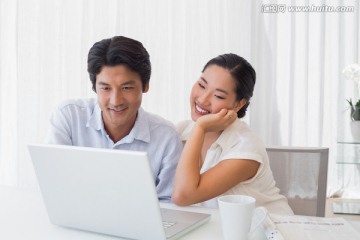 一起微笑着看着笔记本电脑的夫妇