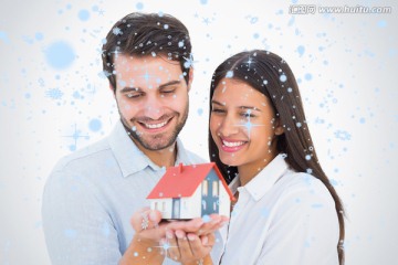 夫妇微笑着捧着房屋模型