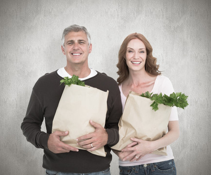 夫妇微笑着抱着购物袋的复合形象