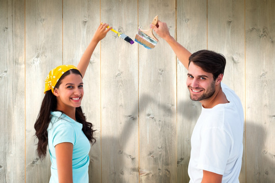 夫妇微笑着粉刷墙的复合形象