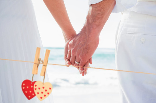 在海邊牽著手的新婚夫婦