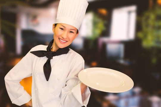 微笑的女厨师拿着一个空盘子