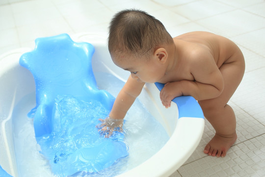 胖胖婴儿扶着洗澡盆玩水