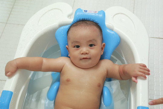 胖胖婴儿躺在洗澡盆里对镜头笑