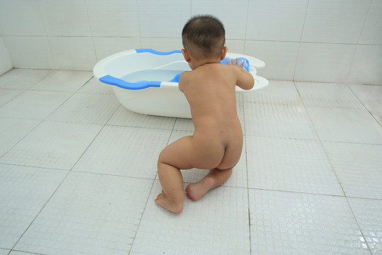 胖胖婴儿趴在装满水洗澡盆上
