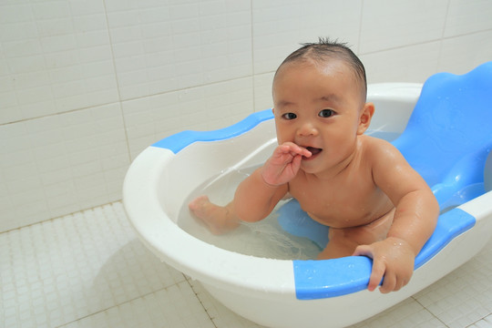 胖胖的婴儿坐着洗澡盆里看镜头