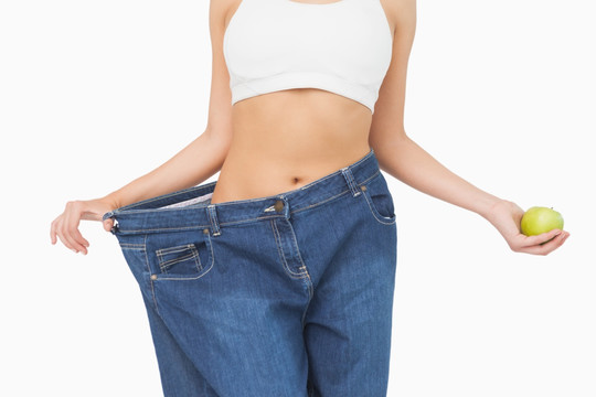 减肥成功的女人拉着牛仔裤腰