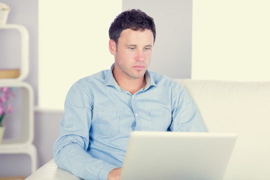 男子坐在沙发上使用笔记本电脑