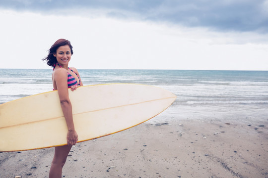 站在海滩上拿着冲浪板的女人
