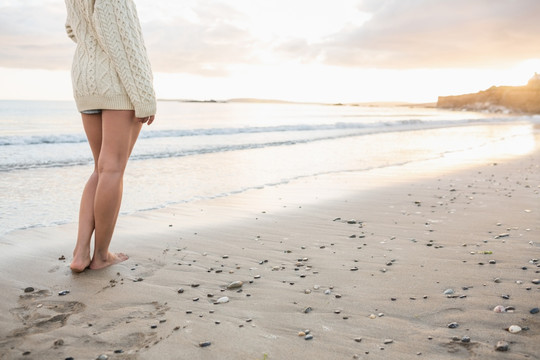 穿着毛衣的女人站在沙滩上