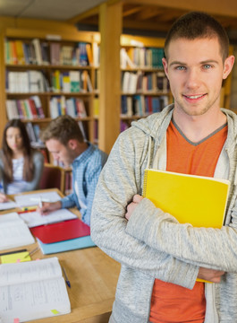 抱着书本男大学生在图书馆里