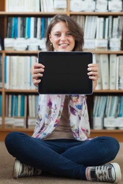在图书馆里展示平板电脑的女学生