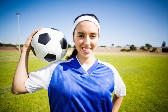 微笑的女运动员拿着足球