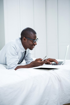 躺在床上使用笔记本电脑的男人
