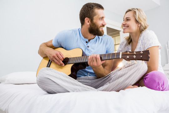 坐在床上弹吉他给老婆听的男人
