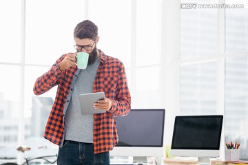 边喝咖啡边使用平板电脑的男商人