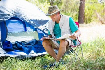 在帐篷旁看书的男人