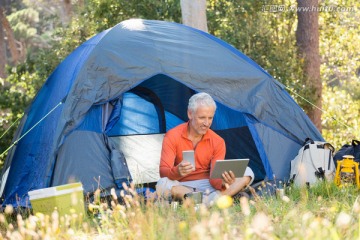 坐在帐篷里用平板电脑的男人