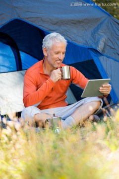 坐在帐篷里的男人在使用平板电脑