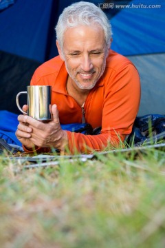 趴在帐篷里的男人拿着杯子