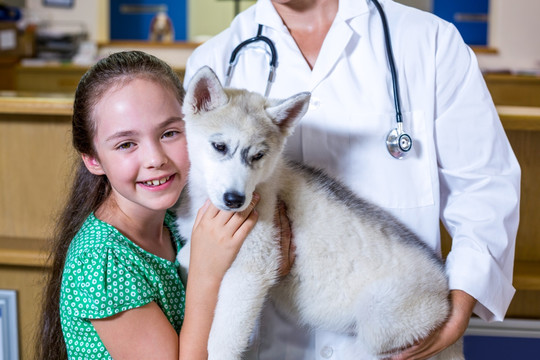 女孩抱着兽医怀里的小狗