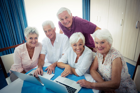 微笑着使用笔记本电脑的老年人