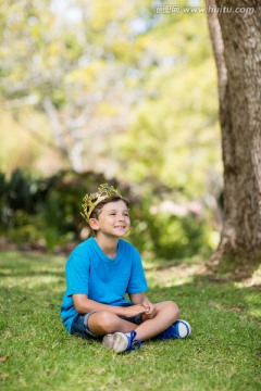年轻男孩戴着一顶王冠坐在草地上